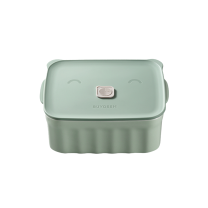A green ceramic bento container with a happy face design on the lid.