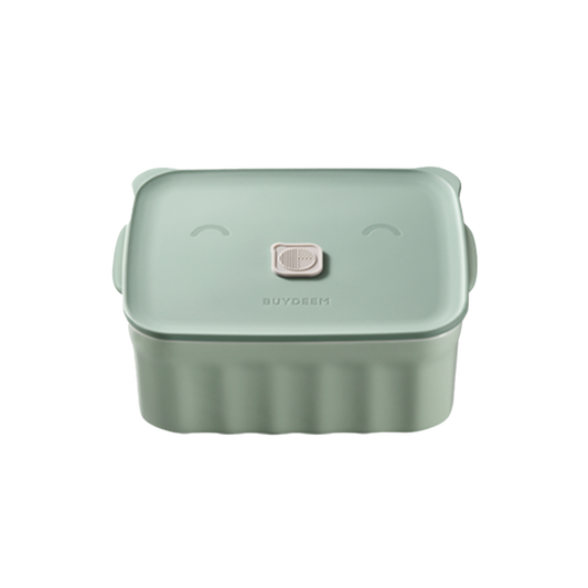 A green ceramic bento container with a happy face design on the lid.